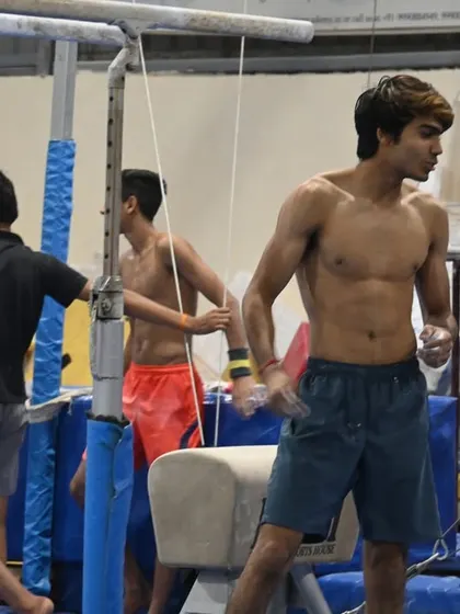 A senior gymnast takes a breather between routines, his physique a testament to his hard work.