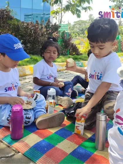 Children share snacks and drinks on a colorful mat. Our field trips are designed to be comfortable and enjoyable, with nutritious snacks provided by the school.