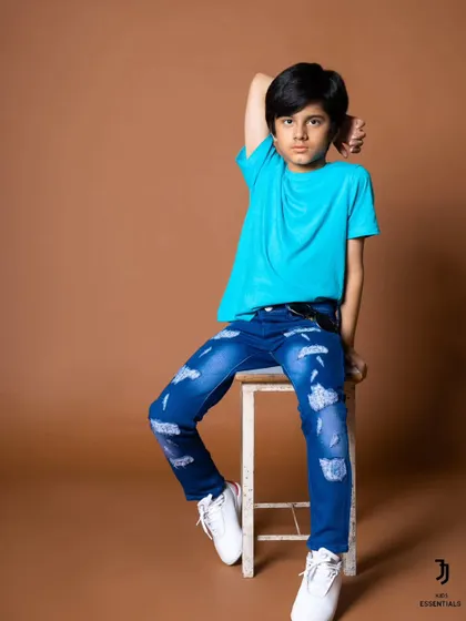 A seated portrait for a kids' jeans brand. The pose is relaxed but stylish, showing off the product in a natural way.