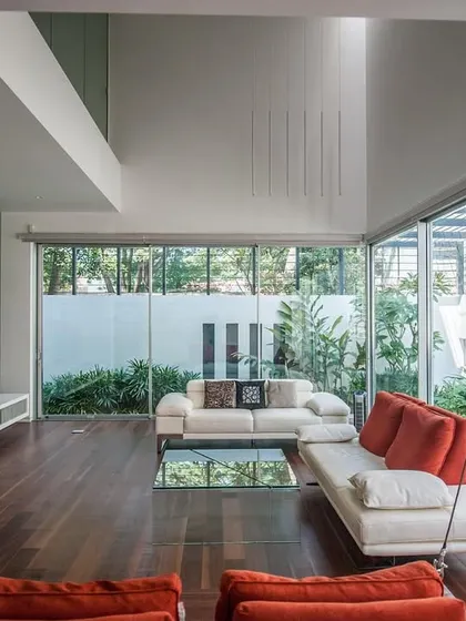 The family room in the Sandeep & Neelam Agarwal residence is wrapped in floor-to-ceiling glass, erasing the boundary with the lush garden outside. An indoor swing adds a playful element to this light-filled, open-concept living space.