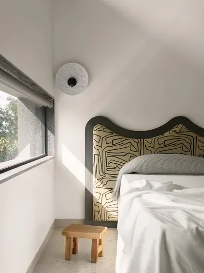 A quiet corner in a Pavilion House bedroom, where a uniquely patterned headboard becomes a piece of art. The design prioritizes natural light and views, creating a serene space to wake up in.