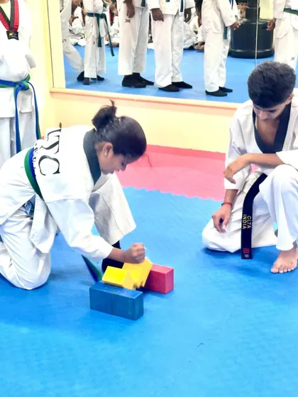 A student breaks through a stack of blocks.