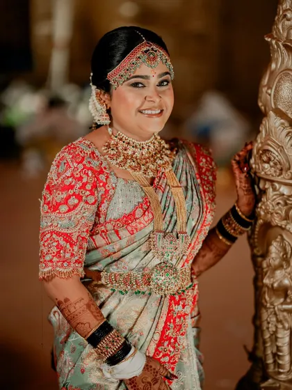 This bride looks absolutely radiant in her wedding attire. The custom red blouse features intricate floral and vine embroidery, perfectly complementing her traditional South Indian bridal look.