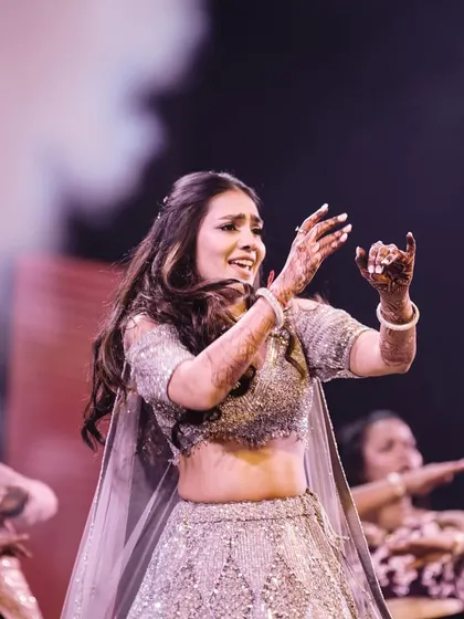 The bride's solo performance on the grand Sangeet stage, captured in a moment of pure joy and energy.