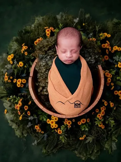 A beautiful overhead shot of a newborn nestled in a wreath of greenery and yellow flowers. This artistic composition creates a stunning portrait.