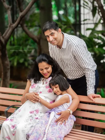 A sweet family photo on a park bench, where the daughter hugs her mother's pregnant belly. These are the moments that show the love of the entire family.