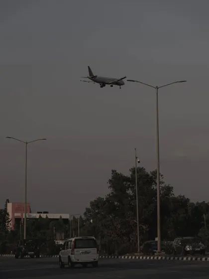 A plane on its final approach, seen over a highway. This image captures the intersection of different modes of transport in a modern landscape.