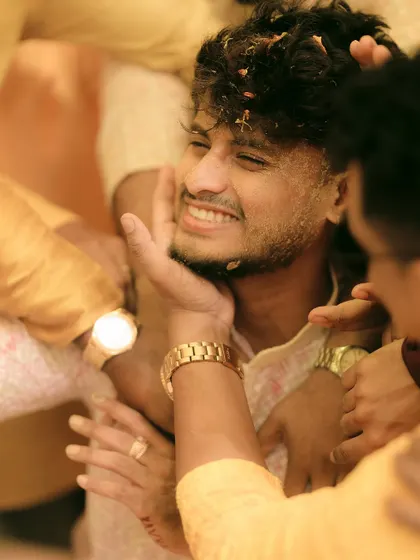 The groom gets lovingly covered in haldi by his friends and family.