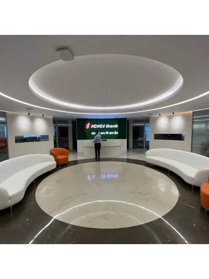 The ICICI Bank reception lobby with a person for scale, illustrating the grand proportions of the space. The circular design naturally guides visitors toward the central reception desk.