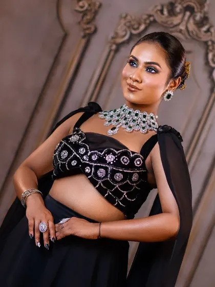 A close-up showcasing the glamorous makeup and stunning diamond and emerald necklace that perfectly complements the black reception outfit.