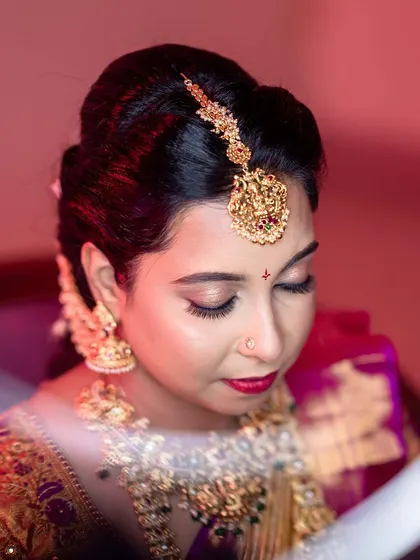 Beauty in every detail. This close-up shot captures the intricate eye makeup and the perfect application of a bold red lip for an early morning muhurtham.