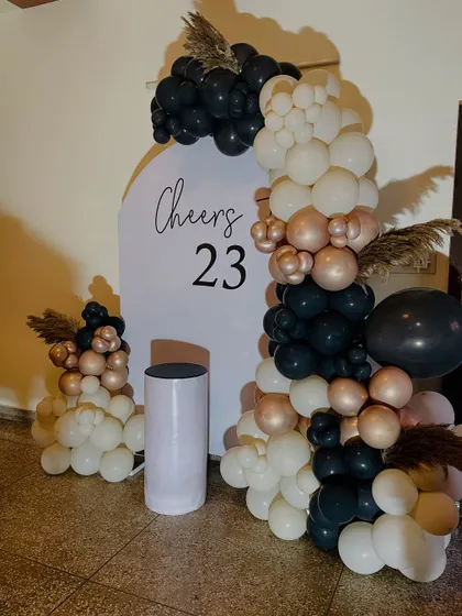 A full view of the chic "Cheers to 23" birthday setup, showing the asymmetrical balloon arch and minimalist backdrop.