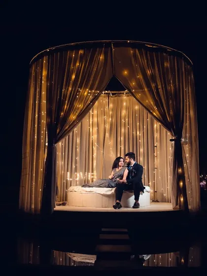 A romantic pre-wedding shot of a couple in an intimate, candle-lit tent, perfect for a save-the-date or engagement announcement.
