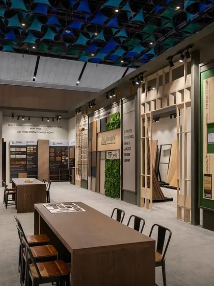Another view of the Realply aisle, showing the extensive wall space dedicated to showcasing plywood and veneer samples. The design incorporates long tables for group discussions and product comparisons.