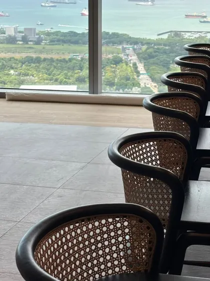 Another angle of the cane-backed bar stools, showing their consistent craftsmanship and how they line up perfectly to create a clean, professional look in a commercial setting with a view.