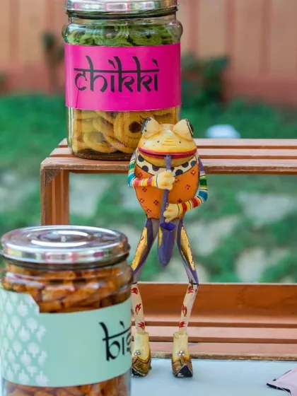 Jars of traditional Indian snacks like chikki displayed at an outdoor event. I love incorporating local flavors and treats into my party setups.