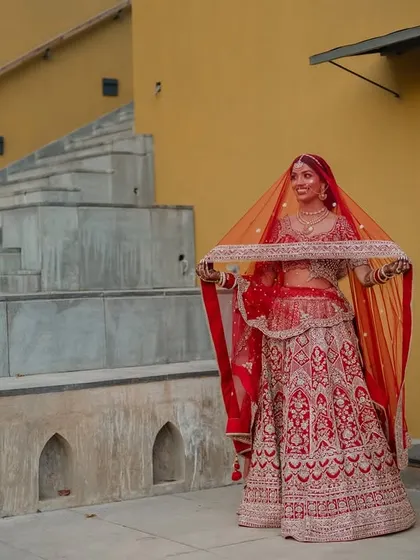 A regal portrait of the couple in their stunning red and cream wedding attire. We use architectural elements like staircases to add a touch of grandeur to our compositions.