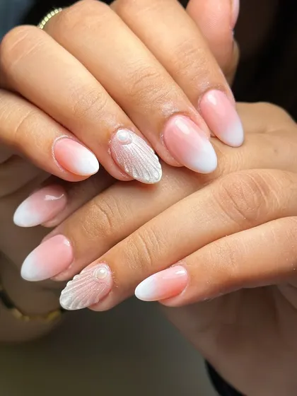 A still shot of the elegant ombre nails with a textured seashell accent. This is a perfect example of a sophisticated beach-themed design.