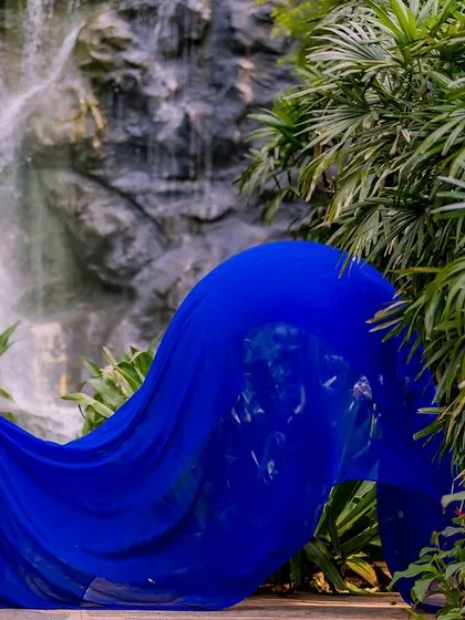 We used a stunning waterfall as the backdrop for this maternity photo. The flowing blue gown mimics the movement of the water, creating a dynamic and natural feel for this expecting couple's portrait.