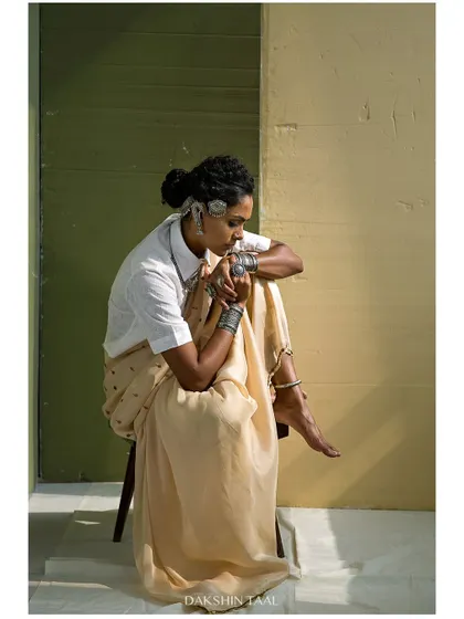 A full-body portrait that captures a moment of quiet introspection. The composition feels balanced and serene, highlighting the graceful drape of the saree.