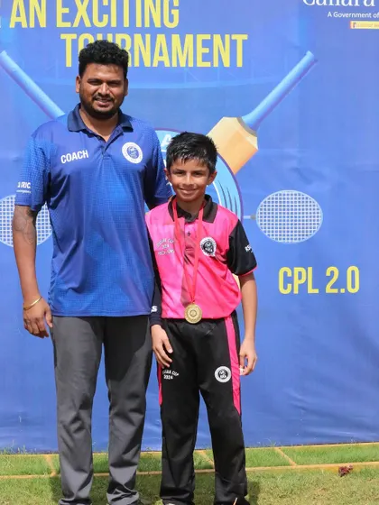 A smiling young player with his medal stands next to his coach for a celebratory picture.
