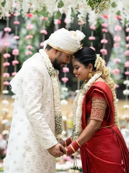 An intimate moment between the couple, their foreheads touching, surrounded by hanging floral decorations.