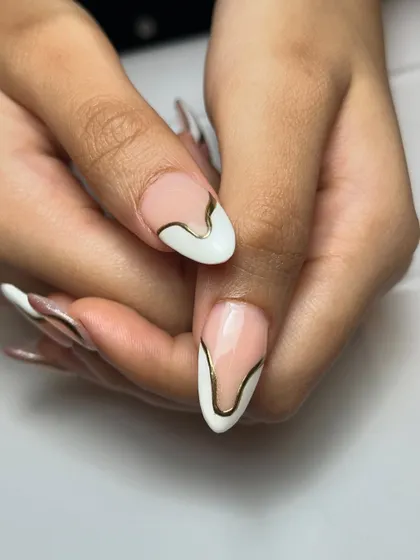 Dramatic curves and high shine. This design layers bold, flowing gold chrome lines over a white and cat-eye French manicure for a truly unique and glamorous look.