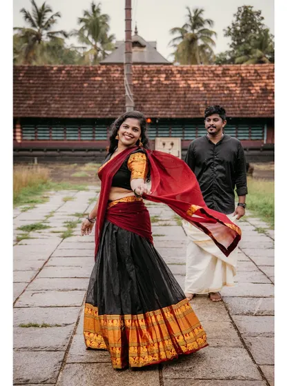 A joyful shot of the bride-to-be leading her partner, her vibrant traditional skirt flowing as she walks.