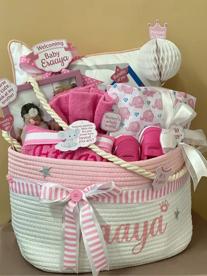 Pretty in pink for baby Eraaya! This personalized rope basket hamper is filled with essentials like onesies, towels, and shoes, all in a beautiful pink and white theme.