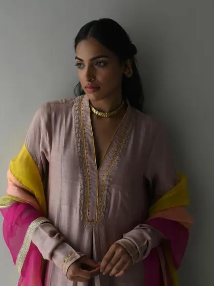 A model looking serene in a dusty pink kurta, accessorized with a multi-colored dupatta that adds a vibrant pop of color.