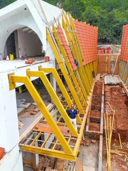 Here I am on-site during the construction of the Tellado Villas' roof. This image captures a critical moment in the building process, showcasing the scale of the yellow-painted steel framework that supports the iconic parabolic, tiled surface.