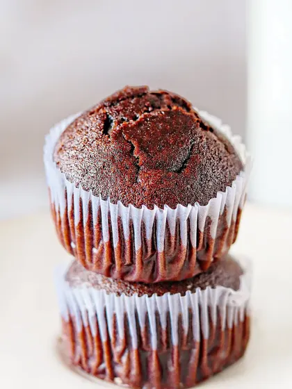 A close-up on a stack of two chocolate muffins. The tight crop emphasizes the crumb and texture, making it look incredibly soft and delicious.