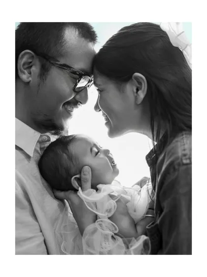 A perfect moment of family bliss. This black and white photo captures the joyful smiles and loving gaze between parents and their new baby.