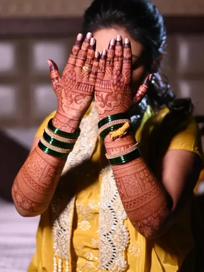 Another classic bridal pose. The intricate back-hand design is fully visible, showcasing the detailed patterns and the beautiful stain.