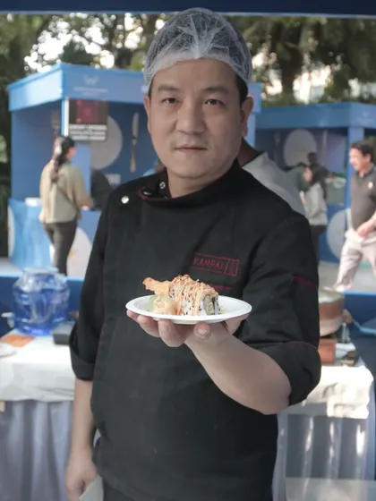 A chef proudly presents a freshly made sushi roll at the World Food Carnival. This highlights the high-quality, authentic international cuisine you can experience at my festivals.