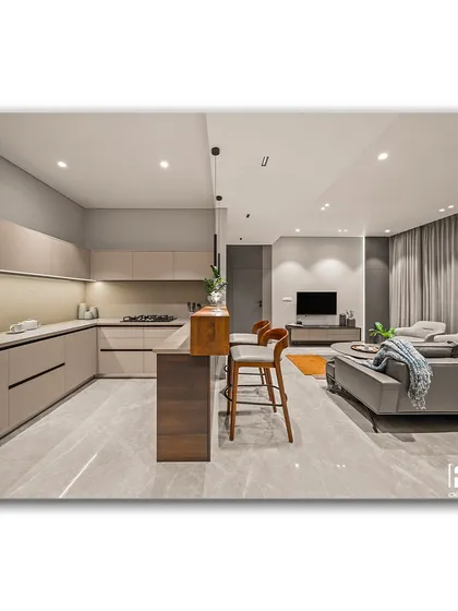 An open-concept living space that exemplifies warm minimalism. The clean lines of the kitchen, the simple bar seating, and the comfortable grey sofa create a cohesive and uncluttered environment that is both stylish and functional.
