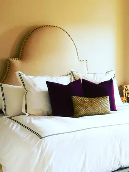 An example of how a warm, neutral wall colour can serve as the perfect canvas. The beige wall allows the rich plum and gold accent pillows to add a touch of luxury.