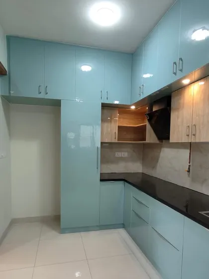 An identical shot of the light blue kitchen, highlighting the high-gloss finish and ample storage.