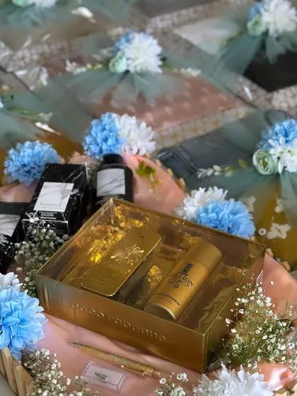 An engagement gift collection featuring a blue and white floral theme. This setup includes gifts for both the bride and groom, such as perfume sets and clothing, all beautifully arranged in coordinated trays.