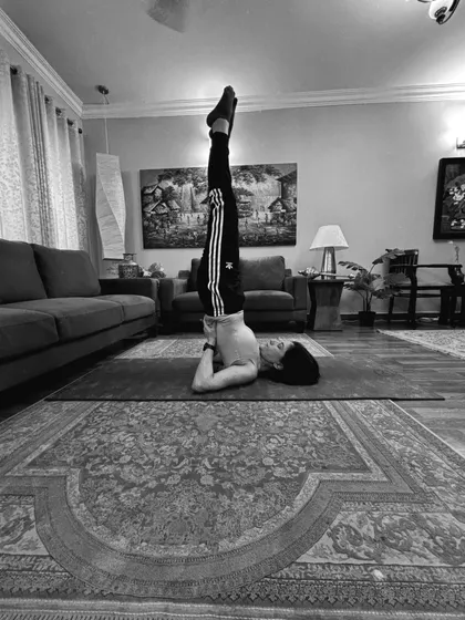 Shoulder stand from a lower angle, toes pointing to the ceiling.