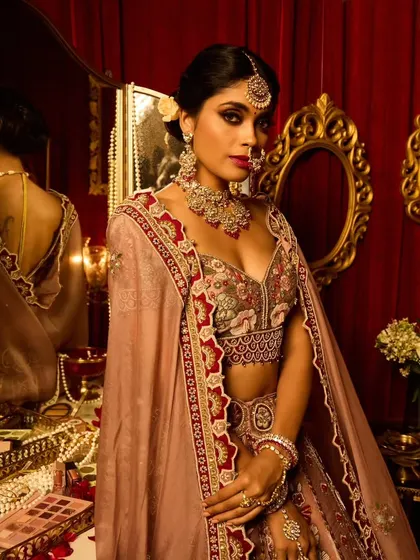 The bride looking in the mirror, a classic shot. The hairstyle is a textured low bun, which is both modern and timeless.