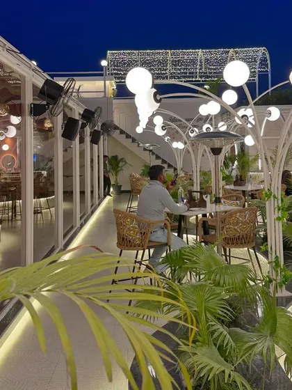 The combination of open sky, lush plants, and glowing lights creates a powerful atmosphere. This is a space designed to feel alive and full of energy.
