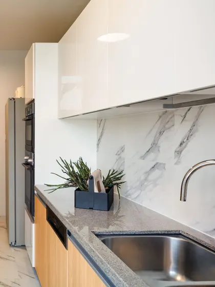 A modern kitchen with a marble backsplash and a mix of wood and white cabinetry, showcasing a clean and functional design.