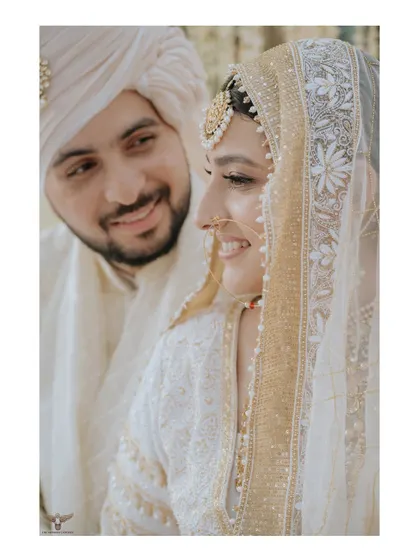 A close-up filled with smiles. This shot captures the couple's joyful and loving interaction, highlighting their happiness and the intricate details of the bride's Nikaah attire.