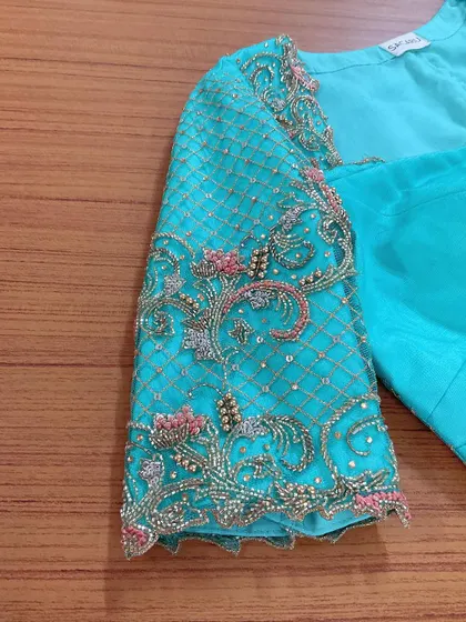 A duplicate image showing the detailed sleeve embroidery on the turquoise blouse.