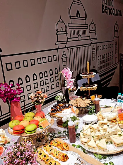 Our hi-tea grazing table set against a backdrop of Namma Bengaluru. The spread includes macarons, donuts, sandwiches, and more, perfect for a stylish corporate event.