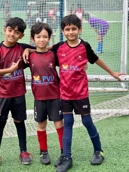 Bonding over the game they love. Three of our young players stand together, showcasing the friendships built at Playsmart.