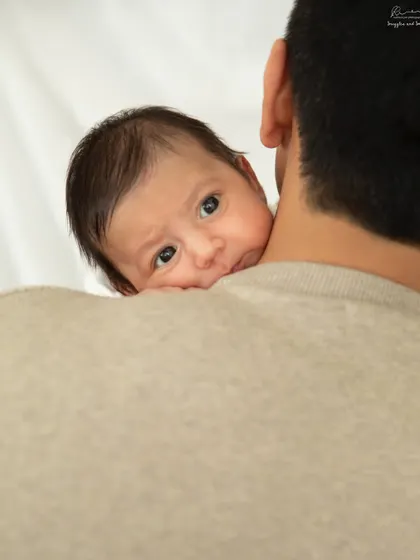 Safe in daddy's arms. This peek-a-boo moment over the shoulder is one of my favorite newborn poses, showing how tiny they are.