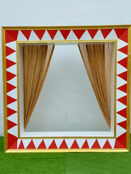A detailed view of the carnival photo booth frame. The bold geometric pattern and shimmering gold curtains create a festive and eye-catching spot for photos at any carnival or circus-themed event.