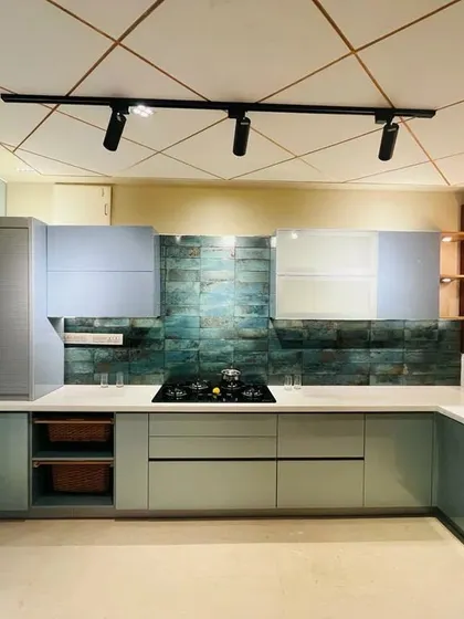 A beautiful kitchen setup with light green cabinets and a textured teal backsplash, demonstrating a fresh and modern color palette.